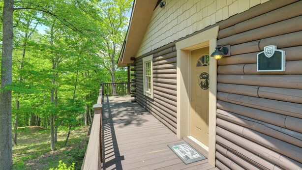 Une cabane en rondins avec un porche, une porte avec une enseigne et une boîte aux lettres.