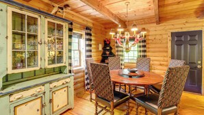 L’intérieur d’un chalet en bois comprend une table à manger, des chaises et un buffet dont les portes sont en verre.