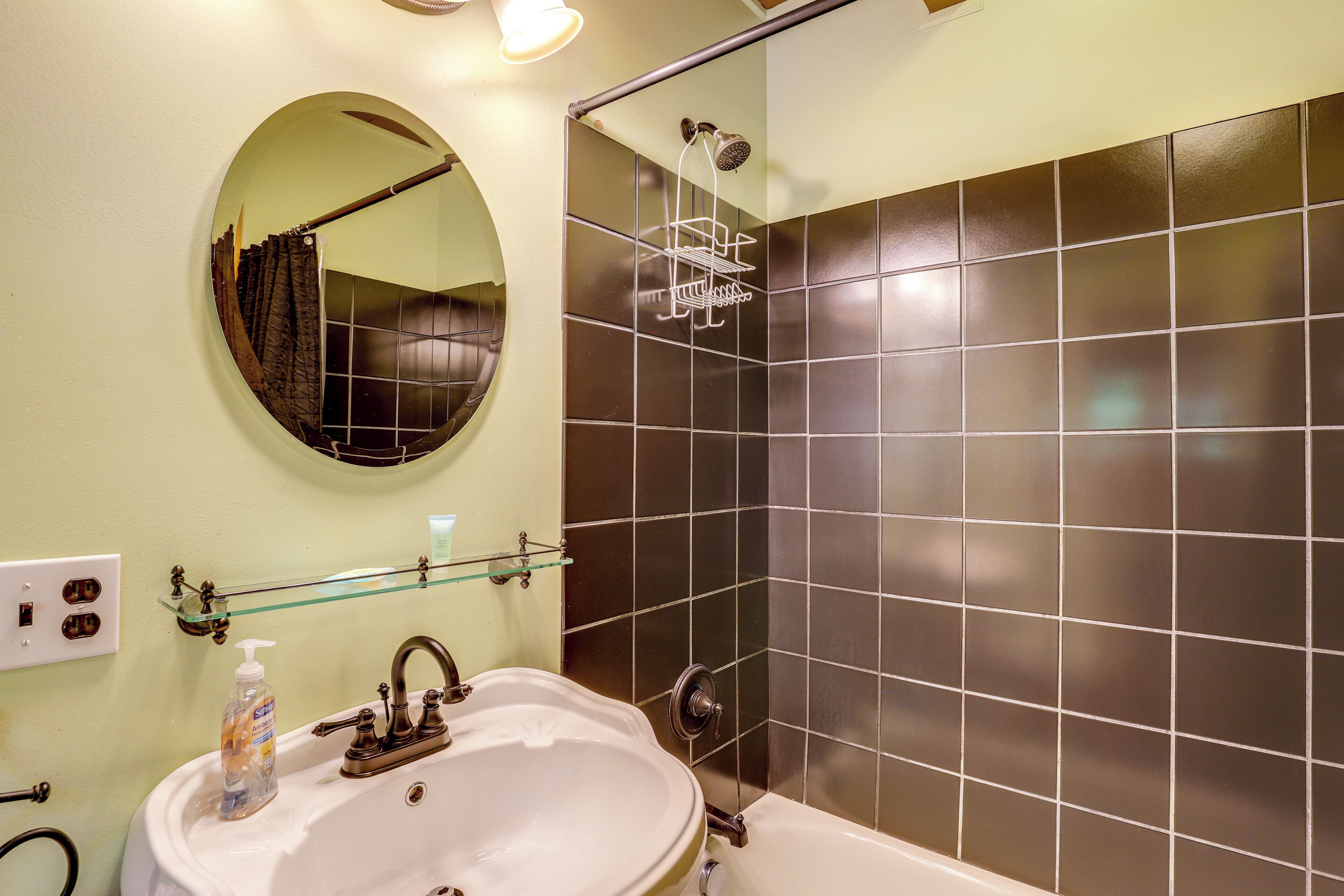 A bathroom with a sink, mirror, and shower.