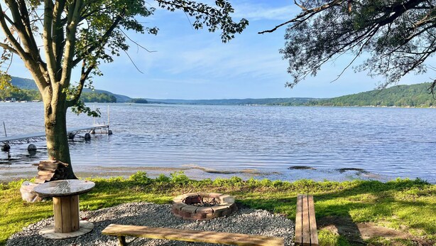 Un espace de pique-nique au bord du lac, équipé d’un banc, d’un foyer et d’une mangeoire à oiseaux.