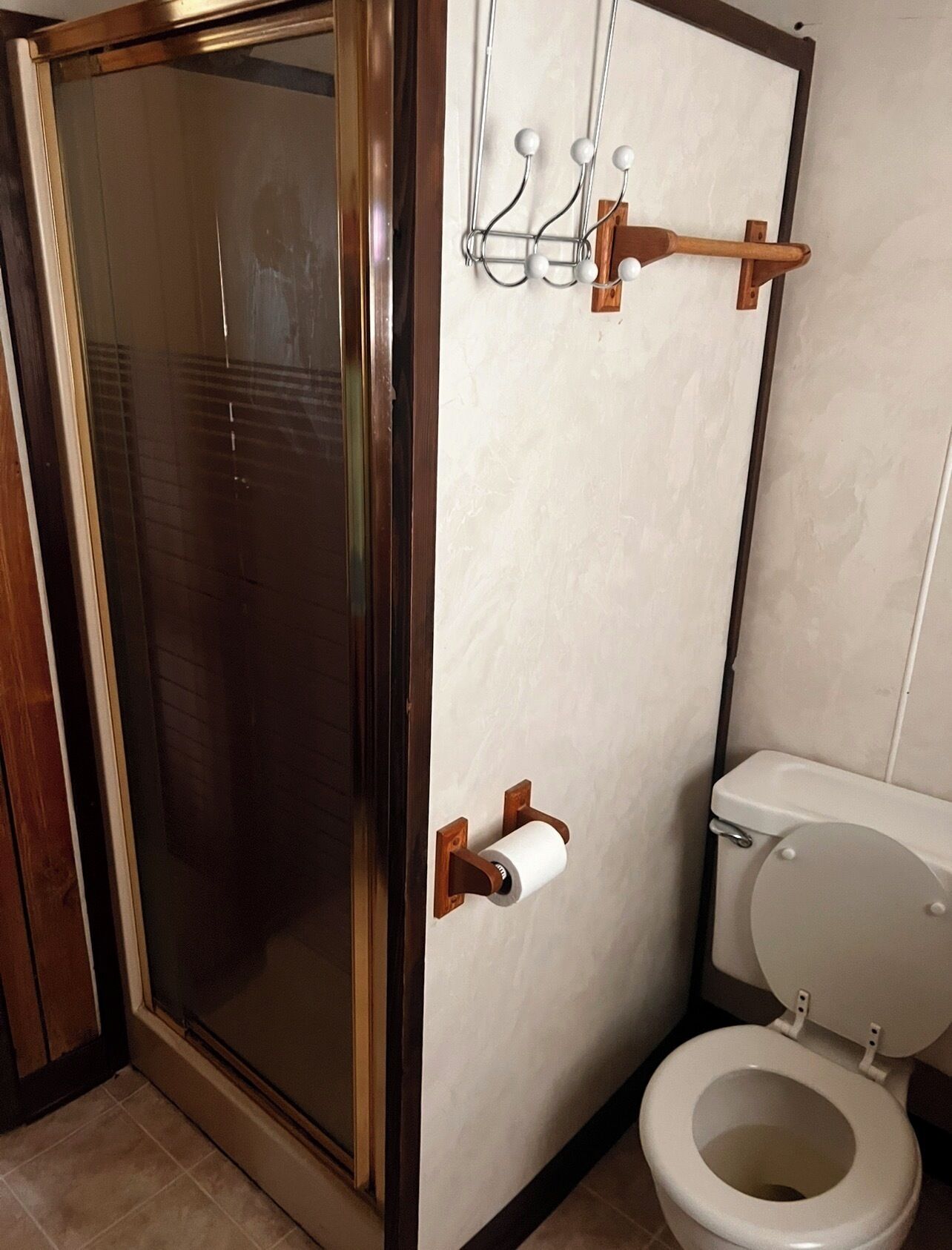 A bathroom with a toilet, a shower enclosure, and a towel rack.