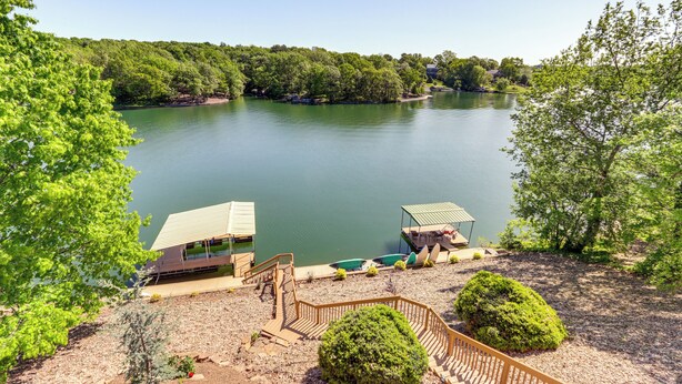 A lakeside property with a dock, a covered seating area, and a wooden deck. - Swim & Boat Docks: Lakefront Gem in Bella Vista! (Bella Vista)