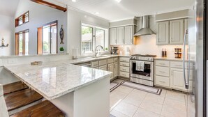 A modern kitchen with white cabinetry, a large island, and stainless steel appliances. - Swim & Boat Docks: Lakefront Gem in Bella Vista! (Bella Vista)