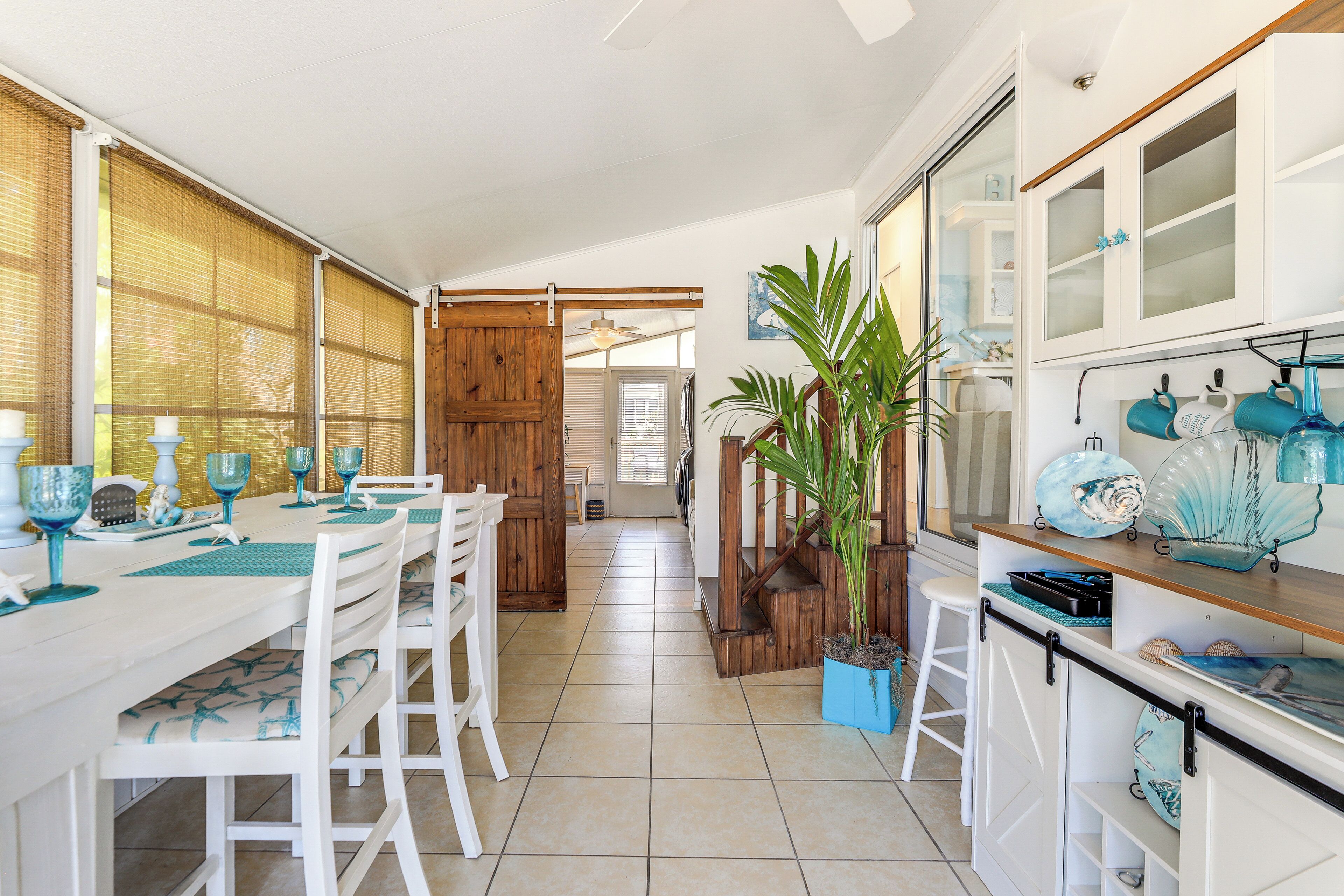 Una cocina amplia con comedor, que cuenta con una isla grande, armarios blancos y una planta en maceta.