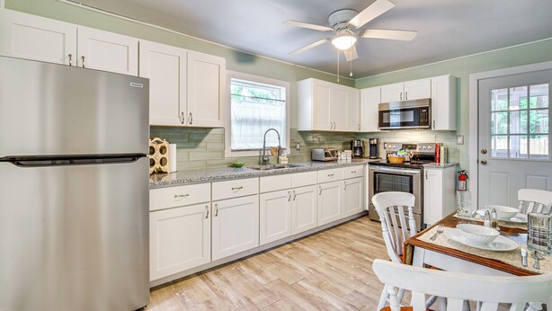 A kitchen with white cabinets, a stainless steel refrigerator, a microwave, and a dining table set for four. - 1 Mi to Ocala Dtwn Square: Home w/ Yard! (Ocala)