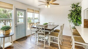 A dining area with a wooden table, white chairs, and a ceiling fan.