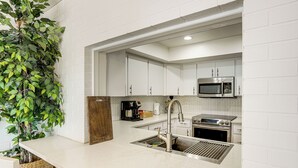 A modern kitchen with white cabinets, stainless steel appliances, and a herringbone-patterned backsplash.