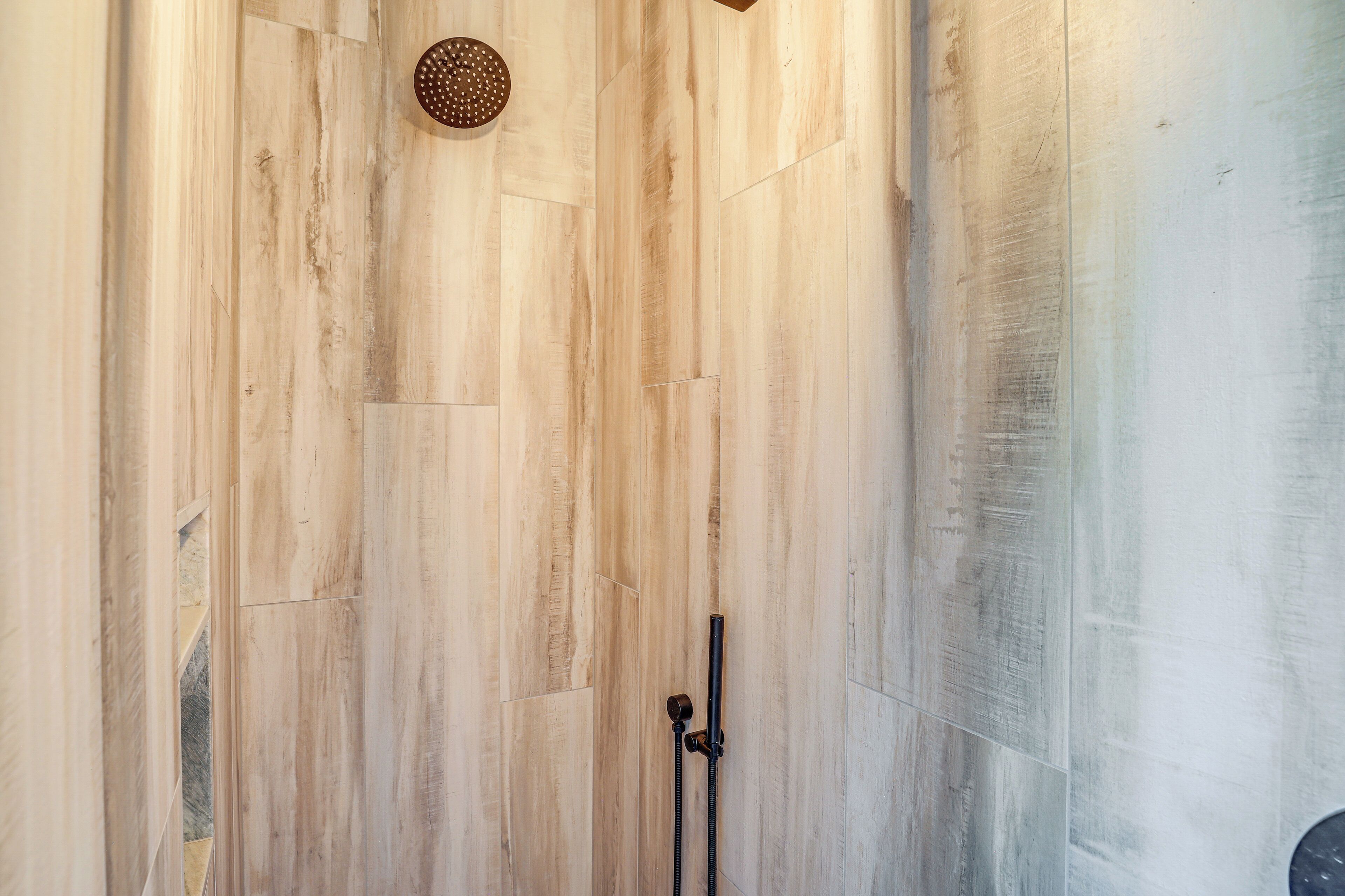 A shower area with wooden walls and a handheld showerhead.