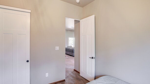 A bedroom with a bed, two white doors, and a hallway leading to another room. - 2 Mi to Lake Almanor: Home w/ Golf Course Views! (Westwood)