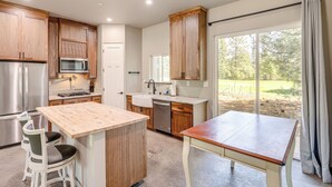 A modern kitchen with wooden cabinets, stainless steel appliances, and a large window offering a view of the outdoors. - 2 Mi to Lake Almanor: Home w/ Golf Course Views! (Westwood)