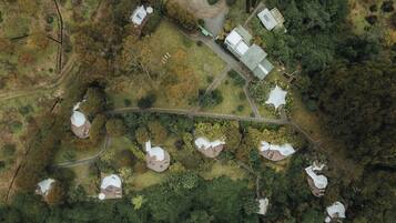An aerial view of a rural property with several dome-shaped buildings surrounded by dense forest.