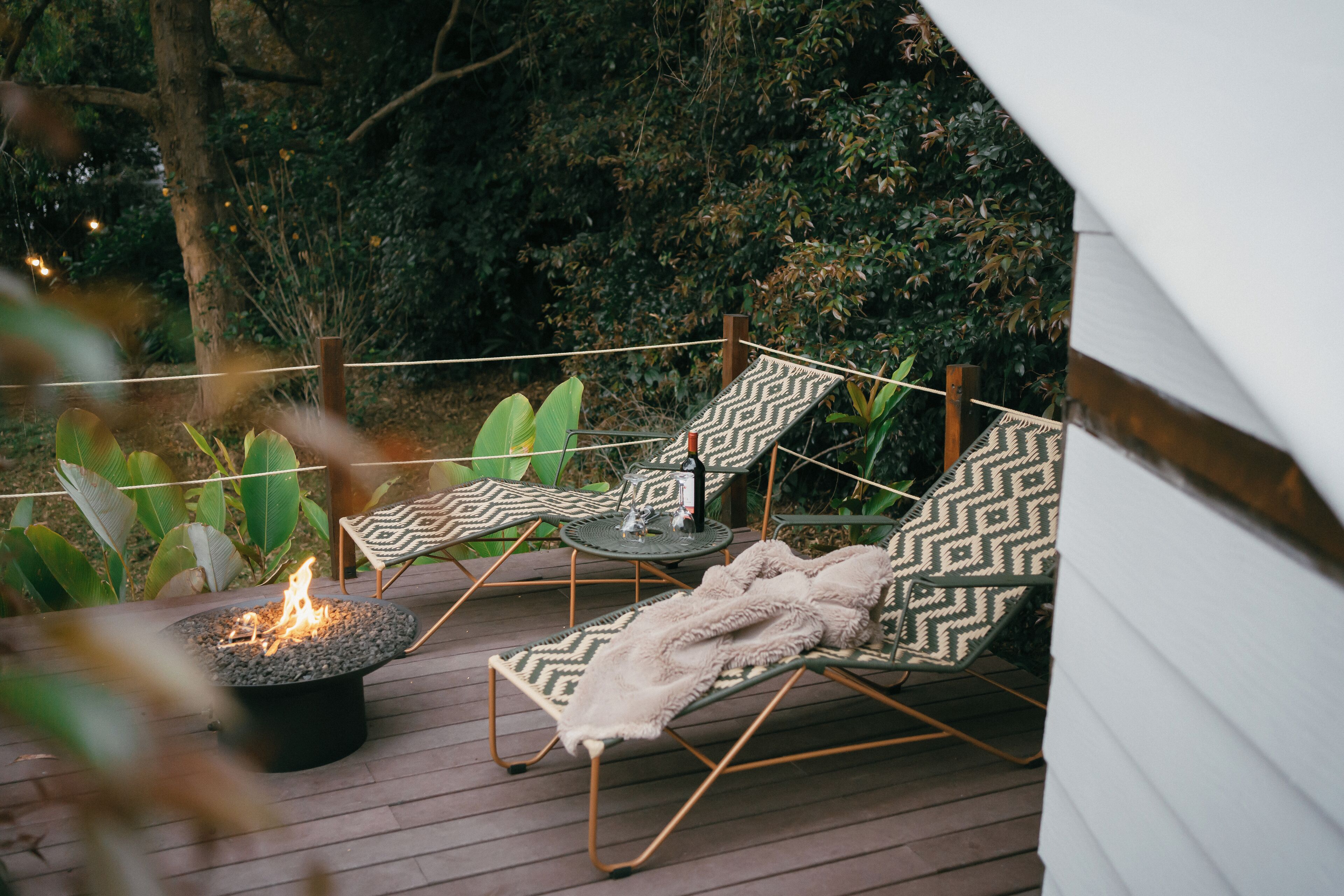 A deck with two lounge chairs, a small table, and a fire pit.