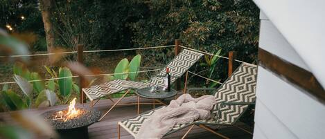 A deck with two lounge chairs, a small table, and a fire pit.
