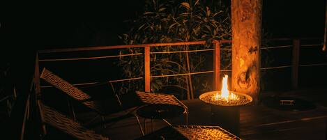 Una terraza con dos sillones de mimbre y una chimenea.