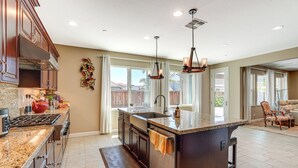 A spacious kitchen with granite countertops, dark cabinetry, and a central island. - Family Home w/ Patio & Fenced Yard in Brentwood (Brentwood)