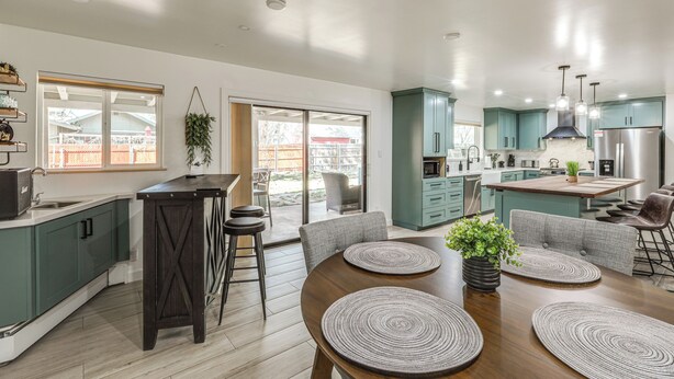 A modern kitchen with teal cabinets, a central island, and a dining area with a wooden table and bar stools. - Walk to Dtwn Flagstaff: Home w/ Great Outdoor Area (Flagstaff)