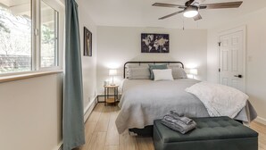 A bedroom with a bed, bedside lamps, a world map artwork, a ceiling fan, and a window with curtains. - Walk to Dtwn Flagstaff: Home w/ Great Outdoor Area (Flagstaff)