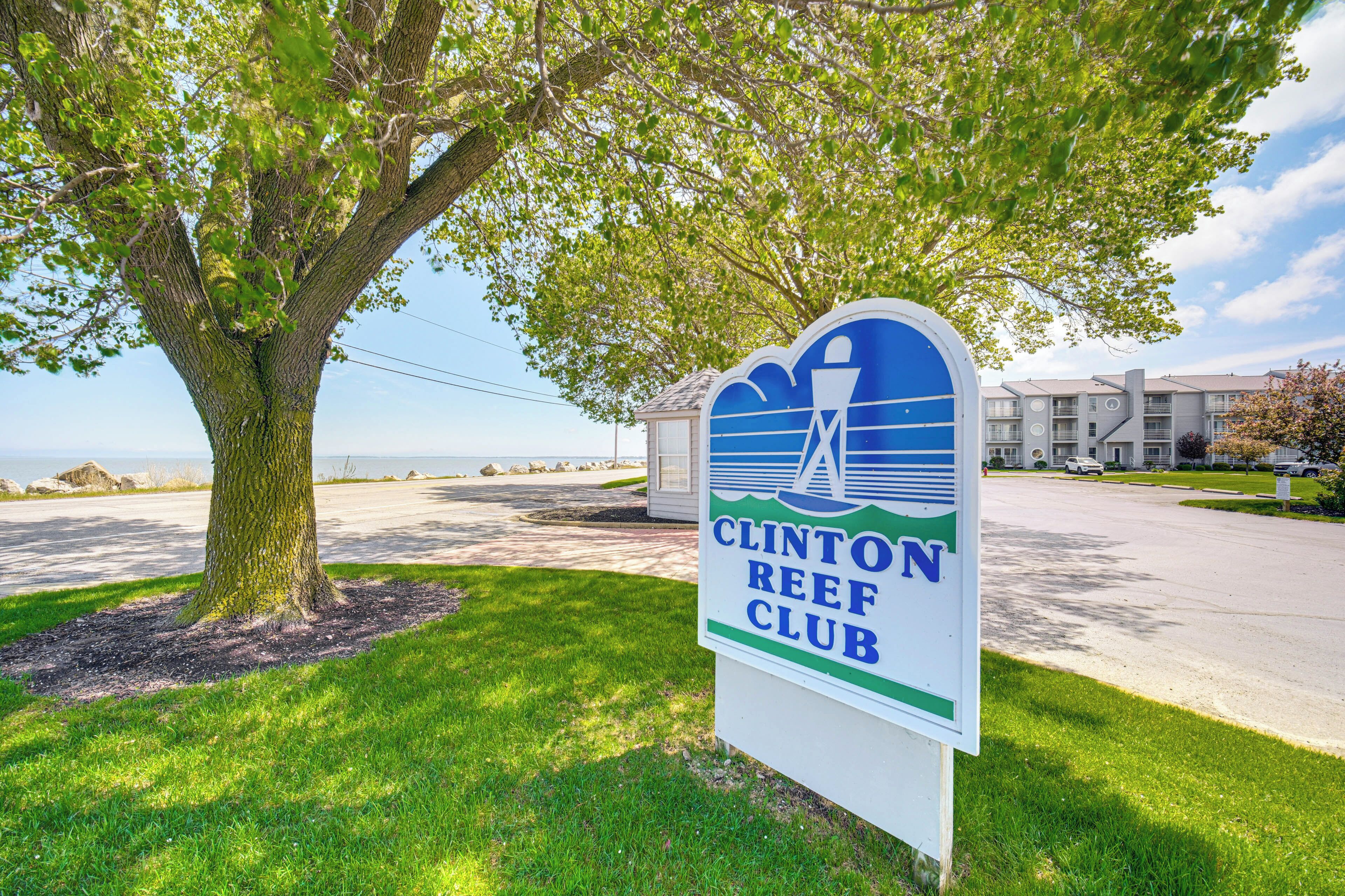 Placa do Clinton Reef Club, com vista para uma árvore e um edifício ao fundo.