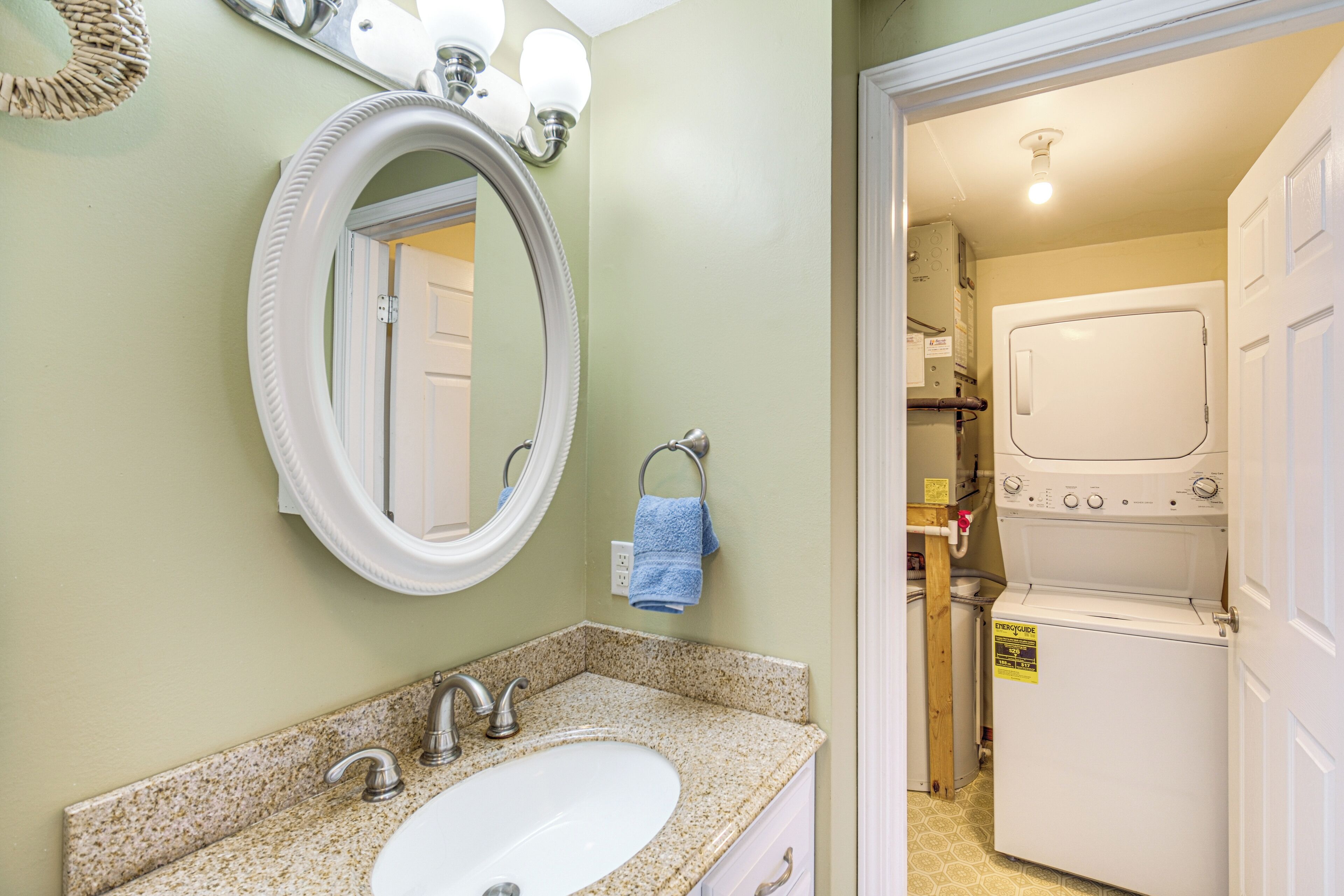 A bathroom with a sink, mirror, and a washing machine.