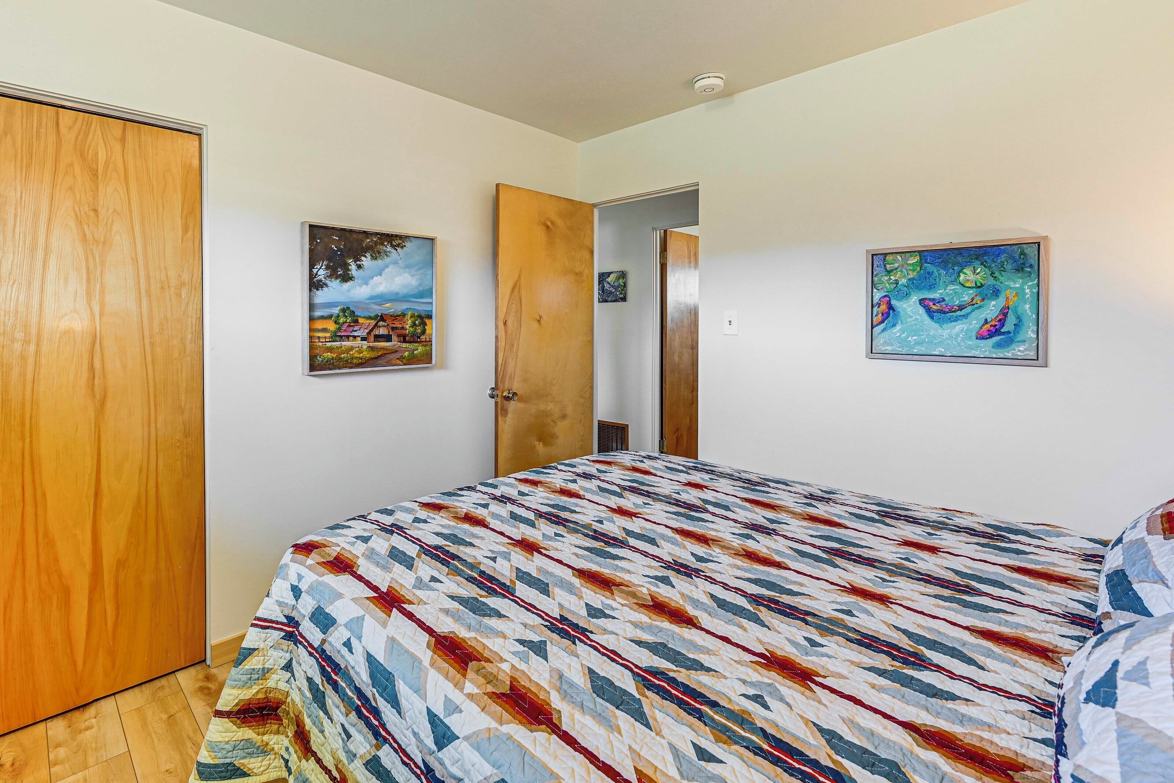 Une chambre à coucher avec un lit, une porte en bois et deux tableaux accrochés au mur.