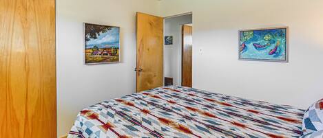Une chambre à coucher avec un lit, une porte en bois et deux tableaux accrochés au mur.