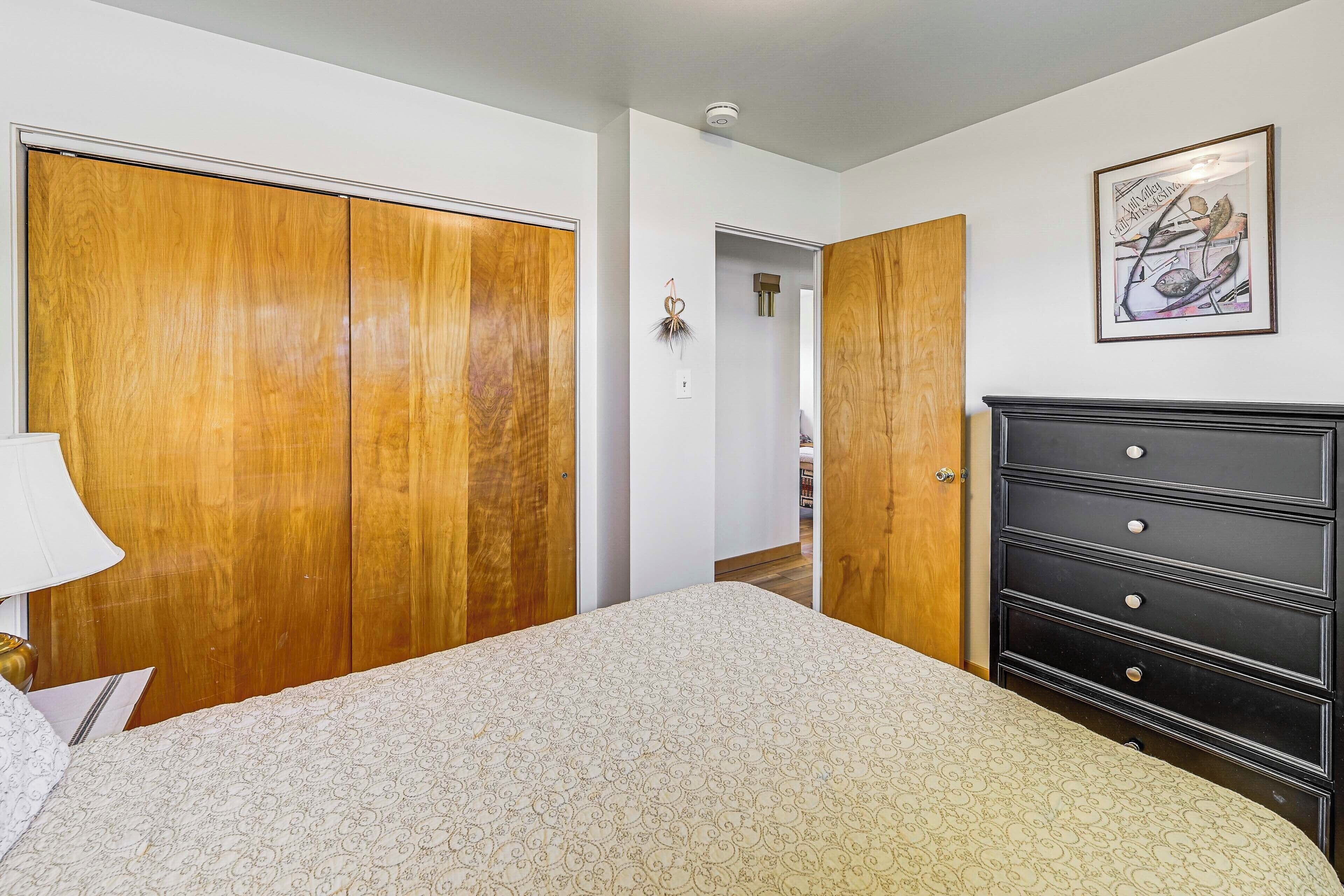 A bedroom with a large bed, wooden wardrobe, and a dresser.