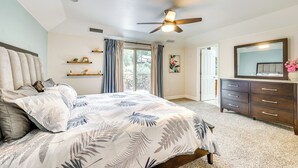 Une chambre à coucher avec un lit, un ventilateur de plafond, une commode et une fenêtre avec des rideaux.