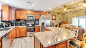 A spacious kitchen with wooden cabinets, stainless steel appliances, and a marble countertop island. - Fish, Swim & More: Lakefront Retreat in Ocklawaha! (Ocklawaha)