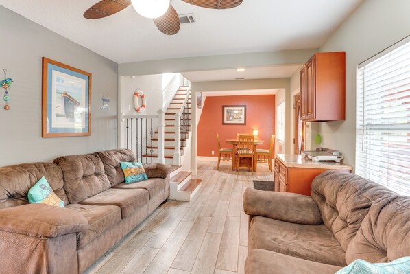 A living room with a brown sofa set, a staircase leading to an upper floor, and a dining area with a table and chairs. - Fish, Swim & More: Lakefront Retreat in Ocklawaha! (Ocklawaha)
