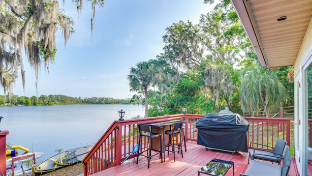 A wooden deck with outdoor furniture, a grill, and a kayak by the water. - Fish, Swim & More: Lakefront Retreat in Ocklawaha! (Ocklawaha)