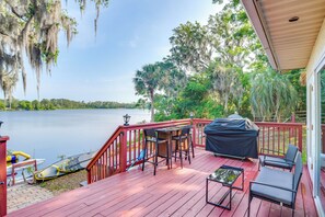 A wooden deck with outdoor furniture, a grill, and a kayak by the water. - Fish, Swim & More: Lakefront Retreat in Ocklawaha! (Ocklawaha)