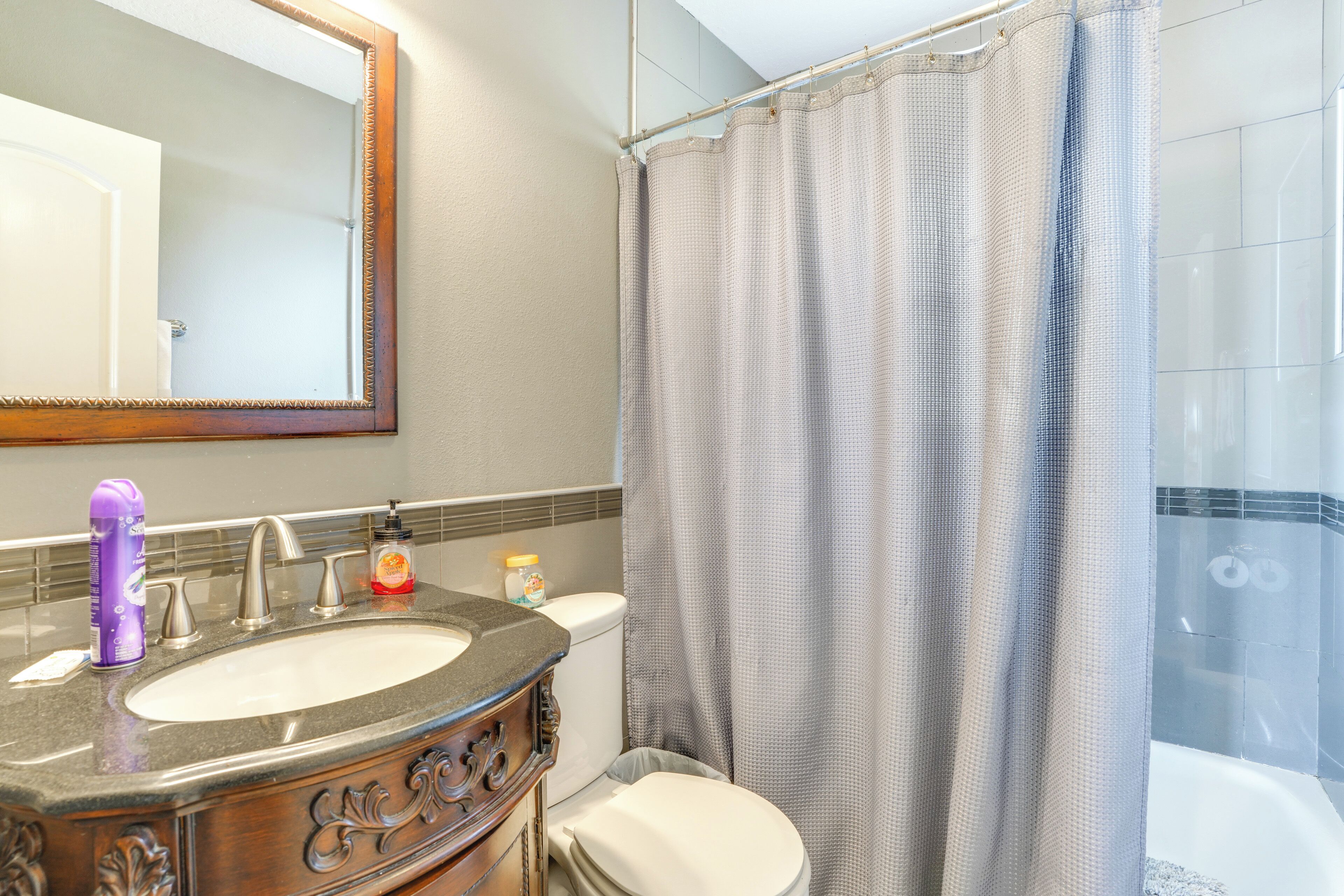 A bathroom with a sink, toilet, and shower curtain.