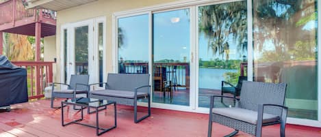 A covered outdoor deck with two chairs and a grill, a sliding glass door leading to a covered patio, and a satellite dish on the roof.