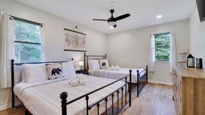 A bedroom with two beds, a ceiling fan, and a wooden dresser.
