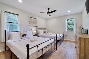 A bedroom with two beds, a ceiling fan, and a wooden dresser.