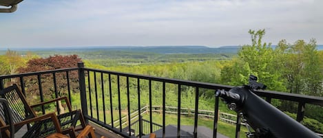 A balcony with a telescope, chairs, and a table with food.