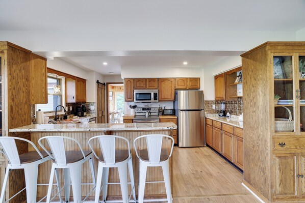 A modern kitchen with wooden cabinets, stainless steel appliances, and a central island with bar stools. - Fall Foliage Mountainside Views, Minutes To Jim Thorpe, Hot Tub & Game Room (Jim Thorpe)