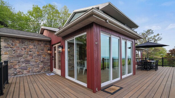 A wooden deck with a stone wall, a glass door, and a patio table with chairs. - Unreal Mountain Views w/ Hot tub Near Charming Jim Thorpe & Blue Mountain Skiing (Jim Thorpe)
