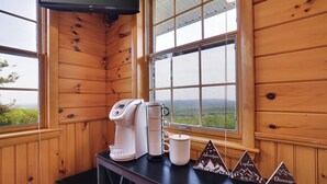 A wooden cabin interior with a coffee maker, mug, and a table with mountain-themed decorations. - Unreal Mountain Views w/ Hot tub Near Charming Jim Thorpe & Blue Mountain Skiing (Jim Thorpe)