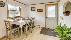 A dining area with a table set for four, wooden chairs, a clock on the wall, and a door with a window. - Day Trip to Acadia: Quiet Coastal Maine Escape (Harrington)