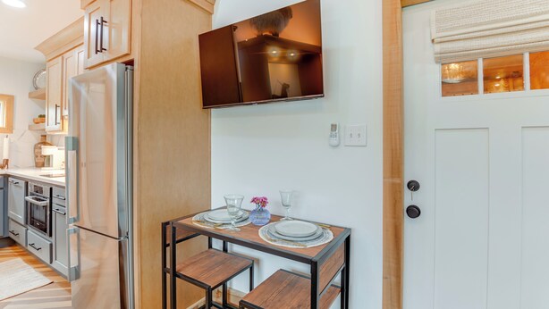 Eine moderne Küche mit Holzausstattung, einem eingebauten Kühlschrank und einer Essecke mit Tisch für zwei Personen.