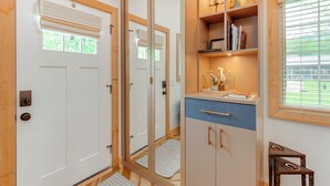 Ein modernes Badezimmer mit Duschkabine aus Glas, einem Waschtisch mit blauer Arbeitsplatte und einem Regal mit Dekoration.