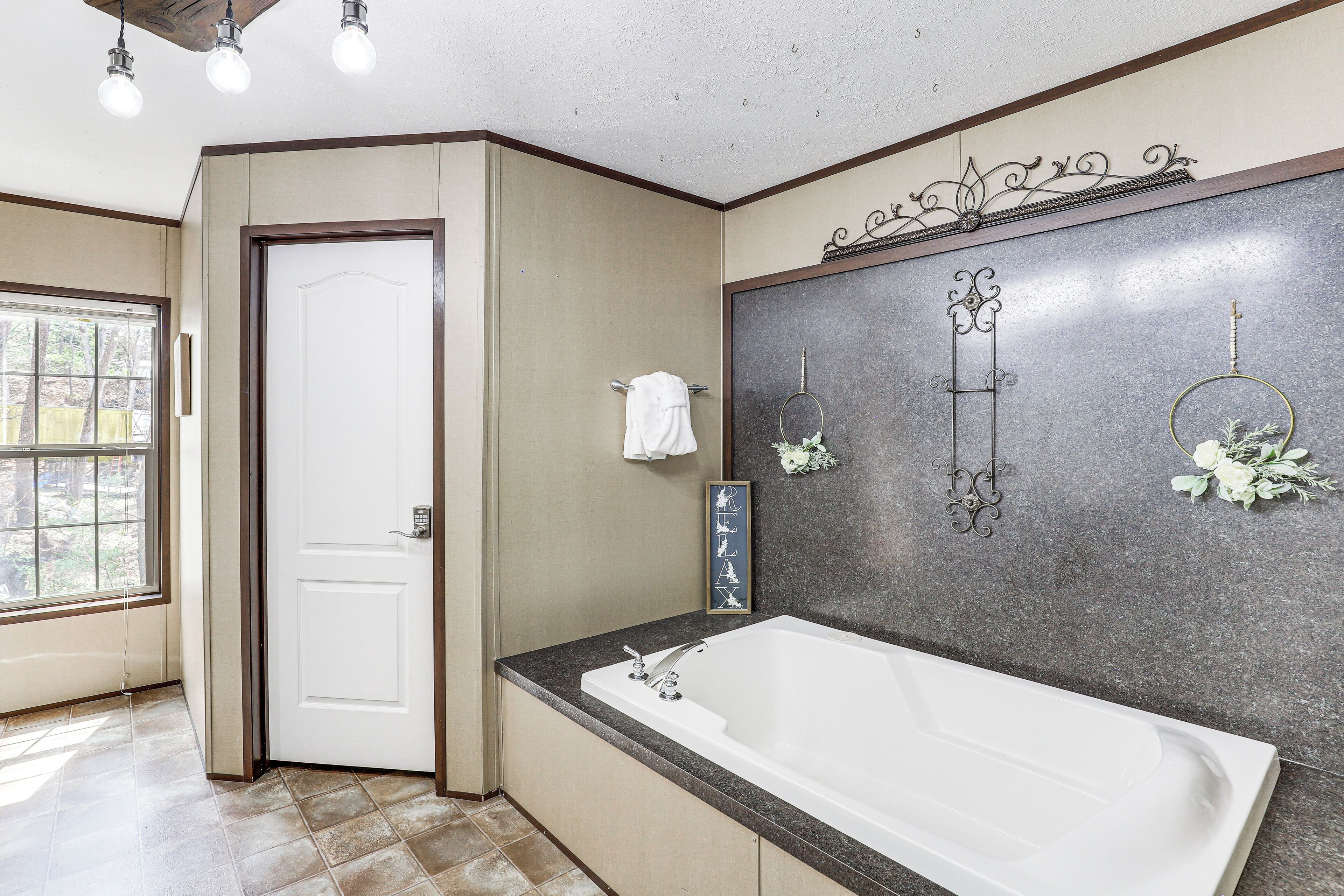 Une salle de bain avec une grande baignoire, une porte et une fenêtre.
