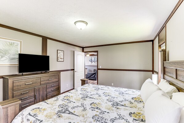 A bedroom with a bed, a dresser, a television, and a door leading to another room. - Scenic Hideaway in Sevierville: Hot Tub + Fire Pit (Sevierville)