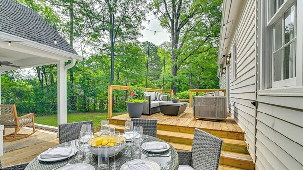 Un patio al aire libre con una mesa de comedor para cuatro personas, rodeado de sillas de mimbre.