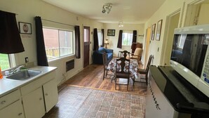 Een keuken met een spoelbak, fornuis en een eethoek met stoelen en een tafel.