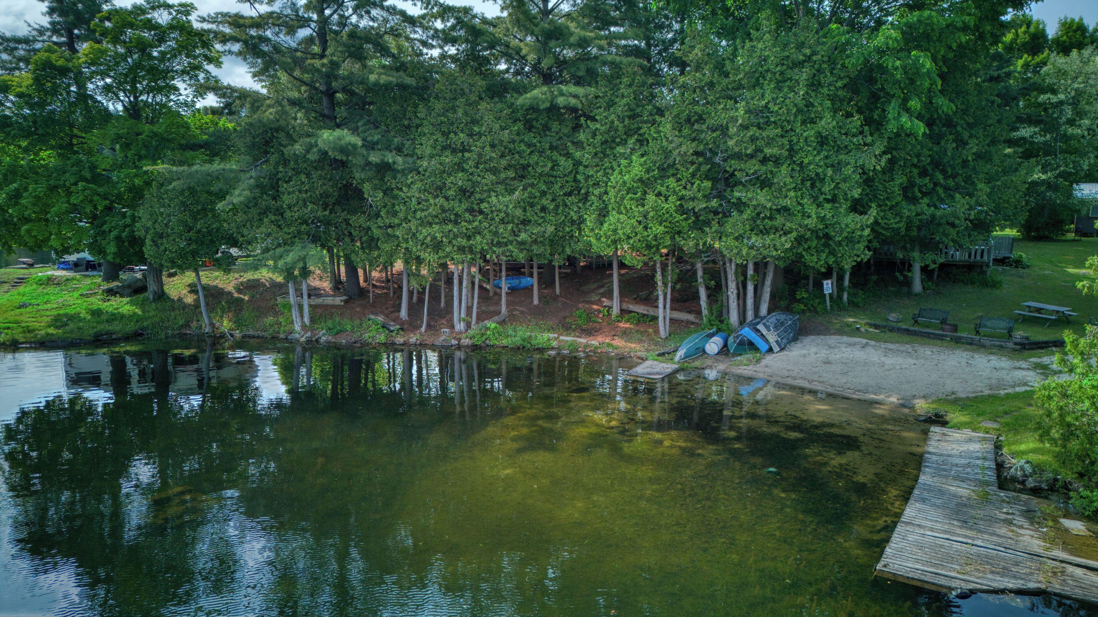 Een gebied aan het water met een pier, picknicktafels en een klein bootenopslag.