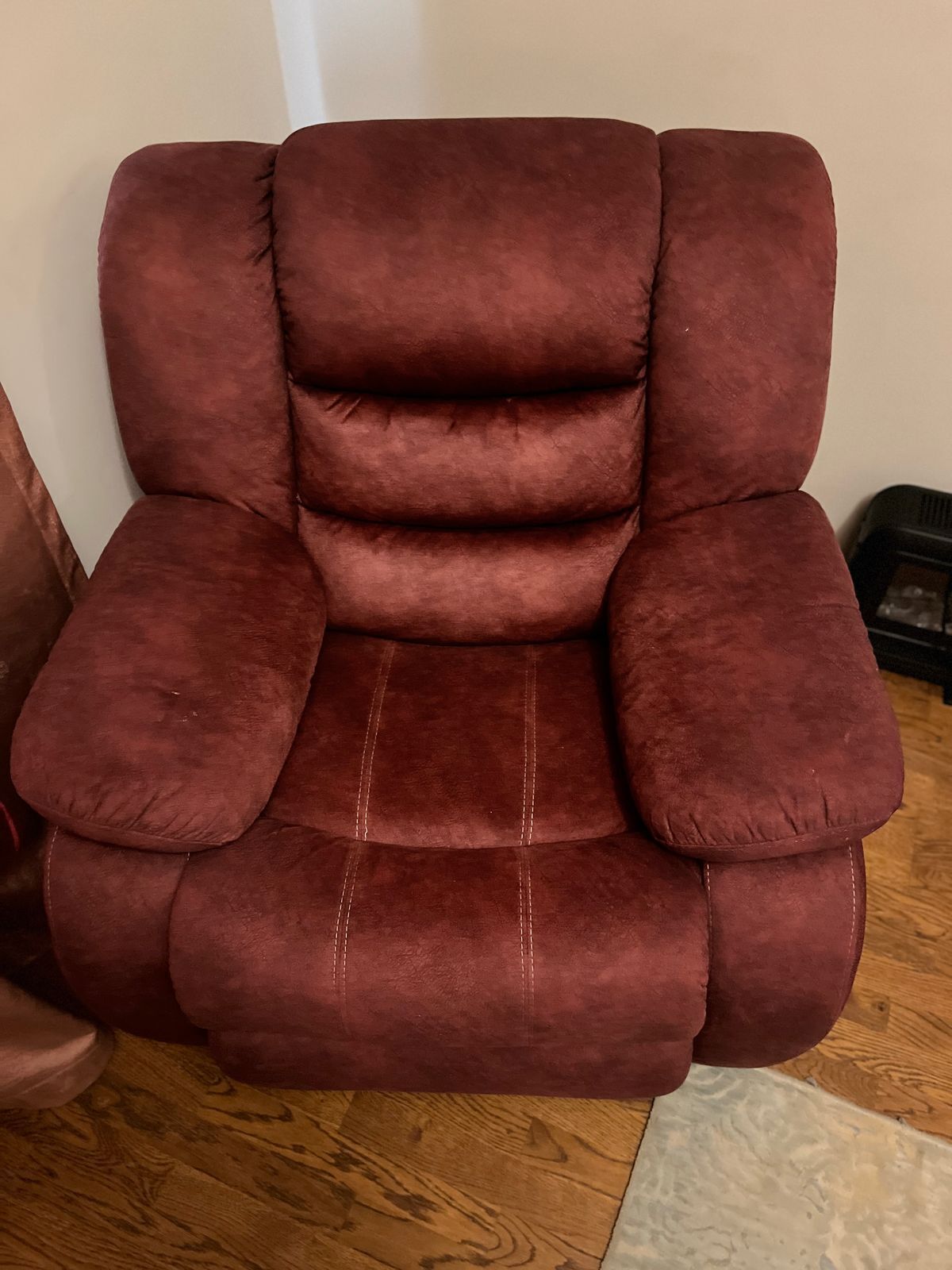 Un fauteuil inclinable rouge, doté d’accoudoirs rembourrés et d’un repose-pieds.
