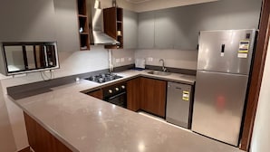 A modern kitchen with a stainless steel refrigerator, built-in oven, and a microwave. - Luxury Stay (6th of October City)
