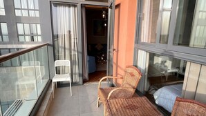 A balcony with wicker chairs, a white chair, and a glass railing. - Luxury Stay (6th of October City)